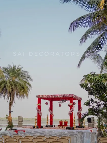A wide shot of the red mandap, showing how it fits into the larger venue space. I always plan the decor to complement the natural surroundings, especially for outdoor events.