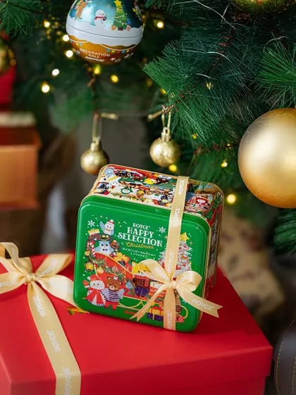 A product-focused shot of a Christmas gift tin placed among other presents under the tree, perfect for a gifting guide.