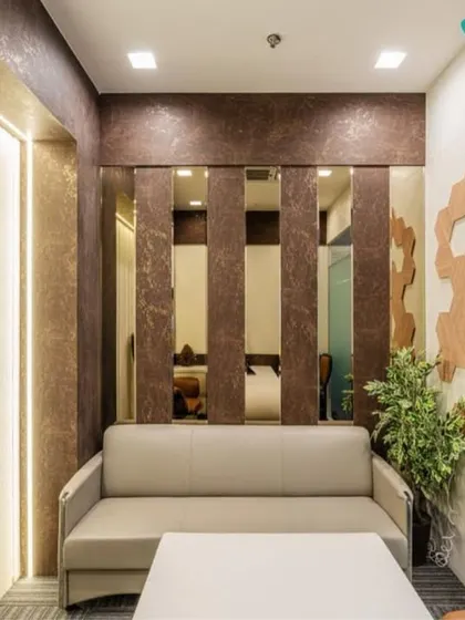 This waiting area combines rich textures and materials. A comfortable sofa is set against a wall with vertical mirrored panels and textured wallpaper, creating a sense of luxury and depth in a compact space.