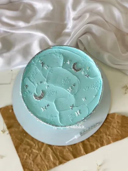A dreamy, sky-blue flat cake with silver moon and star accents. It's a celestial design that's both simple and magical.