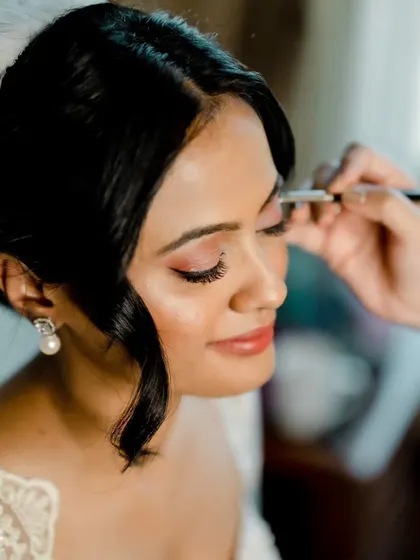 A close-up of the makeup process for a Catholic bride. I'm applying a soft, shimmery eyeshadow to create a romantic and eye-catching look that's perfect for a white wedding.