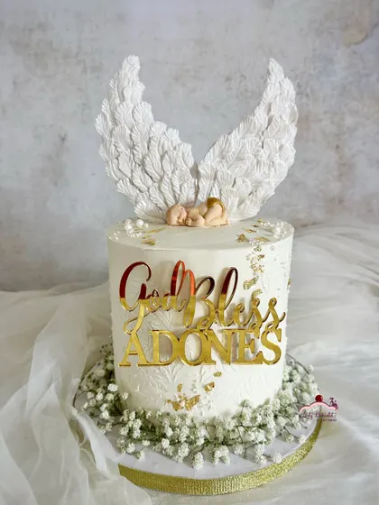 A heavenly baptism cake. This design features a sleeping baby with beautiful, hand-textured angel wings, surrounded by fresh baby's breath.
