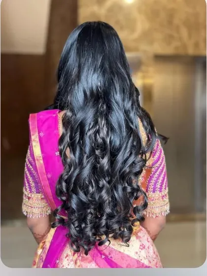 Long, beautiful hair styled into voluminous, cascading curls for a full and glamorous effect.