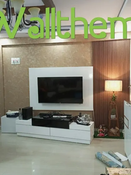 A textured, sand-colored wallpaper installed on a media wall, creating a subtle yet sophisticated backdrop for the television and decor.