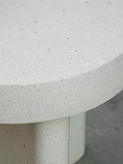 A close-up of a white terrazzo coffee table, showing the fine aggregate and the clean, smooth finish of the surface and edge. This minimalist piece is versatile for any modern interior.