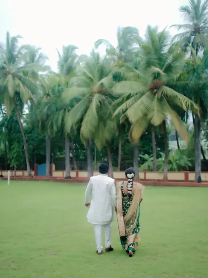 A beautiful shot of the couple walking through a park lined with palm trees, taken from behind to create a sense of journey and togetherness.