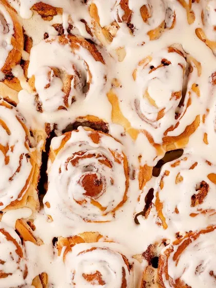 A top-down shot of delicious cinnamon rolls for the dessert shop, It's Minidonuts. This perspective highlights the beautiful swirl pattern and creamy icing, making it a perfect shot for social media feeds.