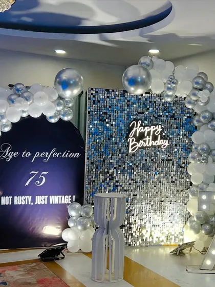 We celebrate life's biggest milestones with style and sophistication. This elegant 75th birthday setup features a dazzling silver sequin wall, a custom neon sign, and large marquee numbers, creating the perfect glamorous backdrop for photos.