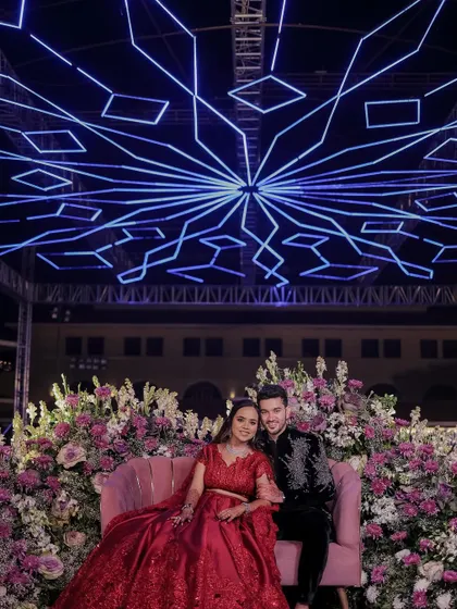 A stunning shot of the couple against a dramatic backdrop. Her smokey eye makeup and red outfit create a look of pure elegance and high-fashion glamour.