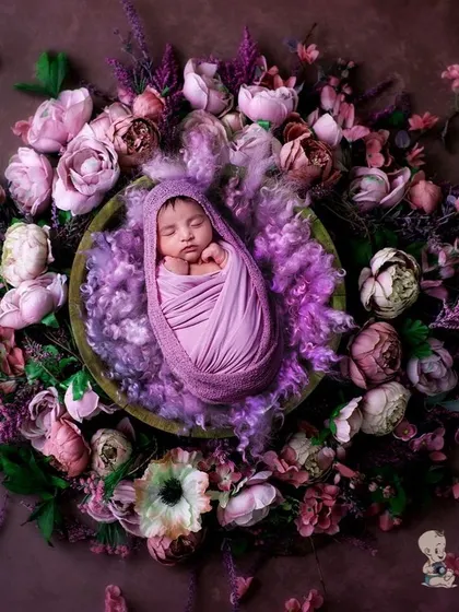 A peaceful newborn wrapped in purple, resting in a basket adorned with a wreath of lavender and purple flowers. The deep, calming colors make for a truly artistic infant portrait.