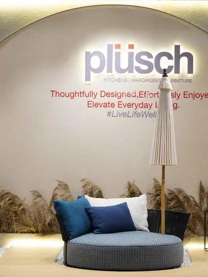 This image showcases the outdoor furniture collection within the Plüsch booth. The circular daybed and umbrella create a relaxed, resort-like vignette, demonstrating the versatility of the brand's offerings.