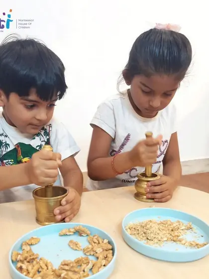 Two boys share a mortar and pestle, learning to cooperate and take turns while preparing ingredients for their healthy Eid dessert.