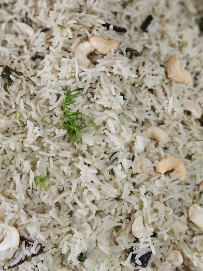 A fragrant white pulao or ghee rice, generously garnished with fried cashews.