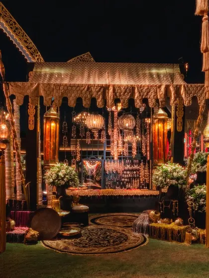 A cozy and opulent seating area from an Arabian Nights cocktail soiree. The canopied structure is adorned with intricate details, traditional lanterns, and plush seating, creating an intimate space for guests.