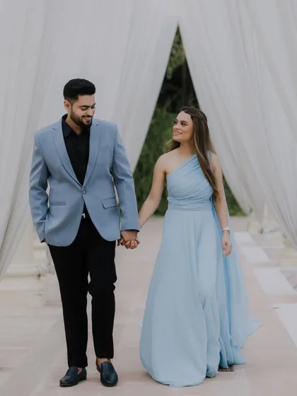 A walk to remember. Tushar and Shriya hold hands as they stroll through a dreamy, curtained walkway during their pre-wedding shoot, creating a scene straight out of a fairytale.