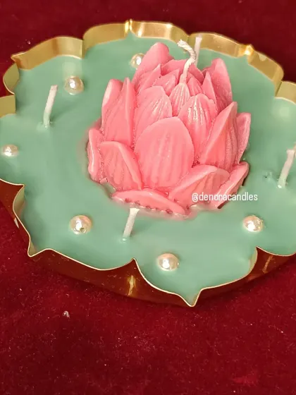 A different angle of the pink lotus urli candle, showing the detail on the petals and the placement of the surrounding wicks.