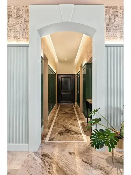 A full view of the arched entrance into the green foyer. The combination of the marble arch, fluted side panels, and architectural wallpaper creates layers of texture and grandeur.