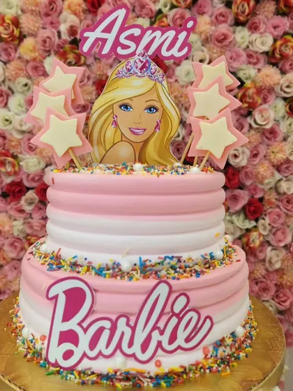A vibrant two-tiered Barbie cake, personalized with a name and decorated with star toppers and sprinkles. It's a dream cake for any Barbie fan.