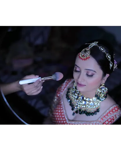 A little behind the scenes magic. Here, I'm applying the finishing touches with a setting powder to ensure the makeup is perfect and long lasting. I use a ring light to see every detail, ensuring a flawless finish.