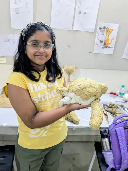 A student proudly holds up her papermache teddy bear before the painting process begins. Building the form is the first and most important step in 3D sculpture.