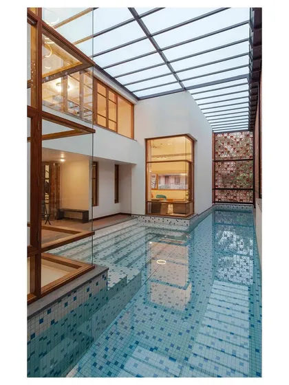 A view of the lap pool from within the 'Pool Court House', showcasing the glass ceiling that floods the area with daylight. The pool is a central feature that organizes the surrounding spaces and acts as a climatic regulator for the home.