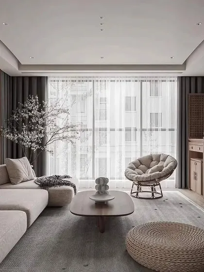 This living room showcases a calm, minimalist aesthetic with a neutral color palette, a comfortable sectional sofa, and a large window for natural light.