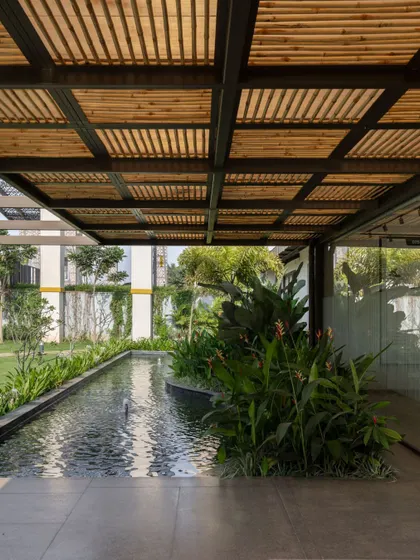 A tranquil water channel runs alongside the walkway at Brigade Oasis, reflecting the sky and the bamboo pergola. This element adds a sensory layer to the experience, creating a calming transition space.