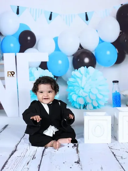 A full view of the Boss Baby first birthday setup, with the little boss sitting happily in his suit. The balloons and "ONE" sign complete the celebratory scene.