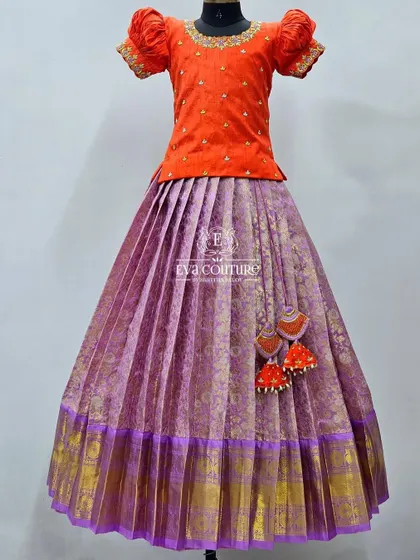 A classic pattu lehenga in orange and purple. The simple, elegant design makes it a timeless piece for women.