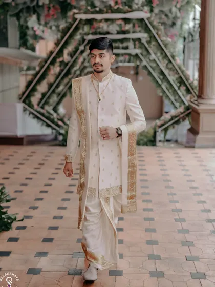 The groom making his entrance at the wedding hall, looking sharp in his traditional outfit.