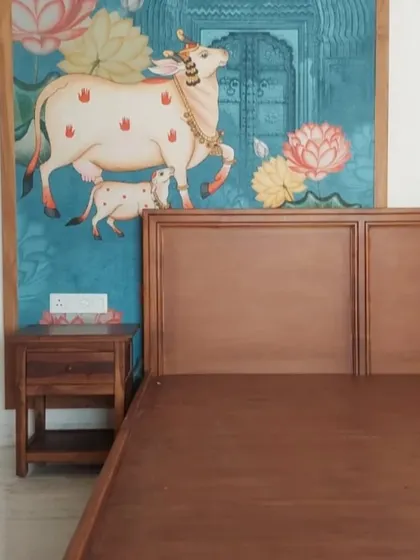 A serene Pichwai cow and calf mural installed as a feature behind a bed, bringing blessings and tranquility to the bedroom.