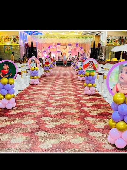 For Riyanshi's first birthday and name revealing ceremony, I lined the aisle with custom balloon pillars featuring her photo. This butterfly-themed decor created a grand and personal entrance for the little one.