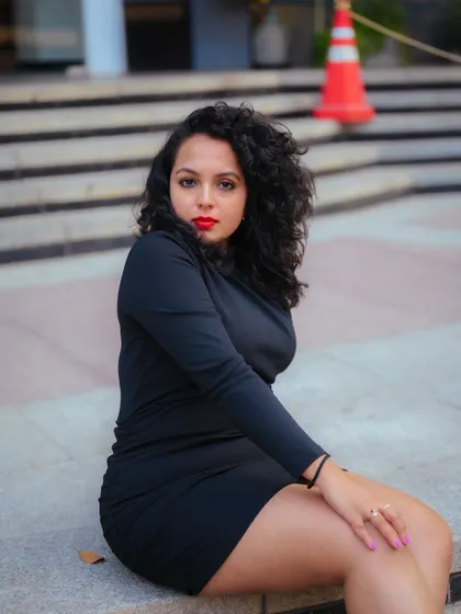 A portrait of a model sitting on city steps. The composition and her relaxed pose create a classic urban fashion image.