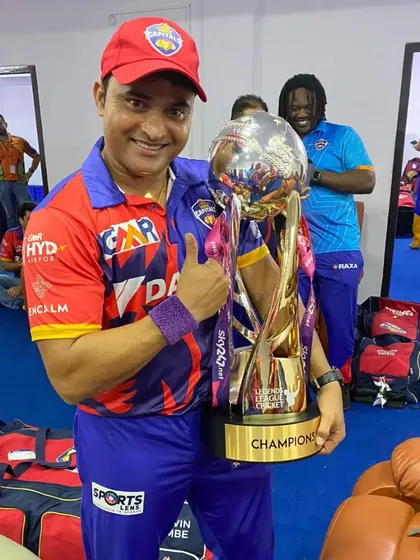 A moment of triumph in the locker room. Pravin Tambe holds the championship trophy, sharing the victory with his teammates.