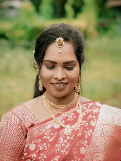 A close-up portrait of the bride, focusing on her serene expression and intricate gold jewelry. This shot highlights her timeless beauty.