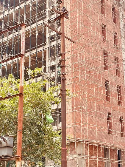 A closer view of the construction site, focusing on the scaffolding and the partially completed brick facade. This image captures the hands-on, industrious nature of the building process.