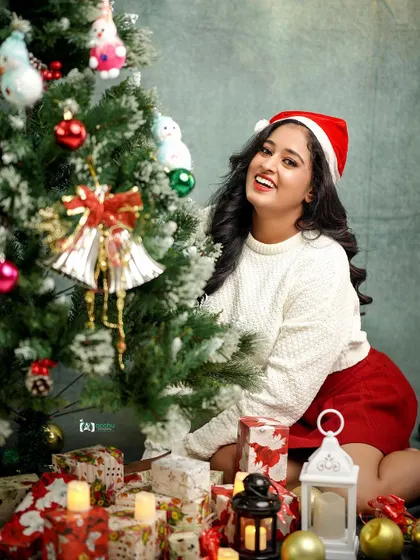 A happy, seated portrait surrounded by Christmas gifts and candles. The warm lighting creates a cozy and inviting atmosphere for this holiday shoot.