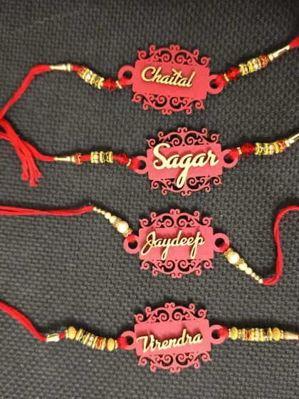 Ornate laser-cut MDF rakhis in a vibrant red color, personalized with names in a beautiful script.