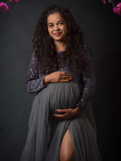 A gentle, classic pose for a maternity portrait. The focus here is on the mother's happy expression and the loving way she holds her baby bump, creating a warm and timeless memory.