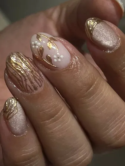 An elegant and intricate design featuring a shimmery nude base with delicate, hand-painted gold floral and leaf patterns.