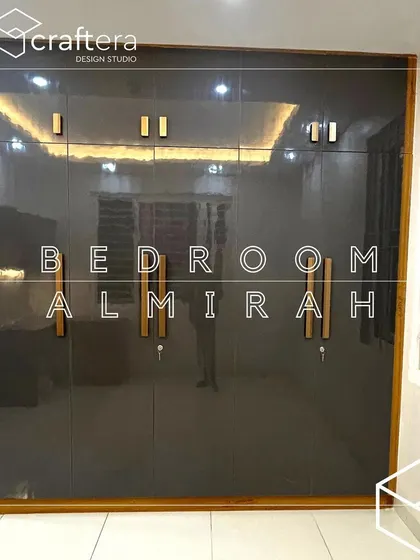 A high-gloss grey finish wardrobe with custom wooden handles. This floor-to-ceiling almirah provides ample storage and its reflective surface adds a touch of modern luxury to the bedroom.