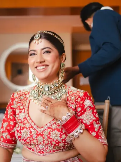 The bride's infectious smile as she gets her final jewellery pieces put on. This candid getting-ready shot is full of happiness and excitement.
