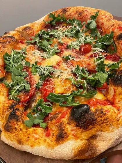 A beautiful artisan pizza topped with fresh arugula and grated parmesan. The peppery arugula provides a fresh contrast to the rich cheese and tomato sauce.