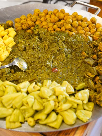 A large tawa filled with the components of a traditional Gujarati Undhiyu, showcasing the fresh, seasonal vegetables we use.