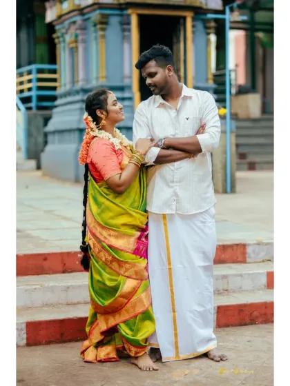 A full-length view of a couple on temple steps, dressed in vibrant South Indian attire. A perfect blend of tradition and candid romance.