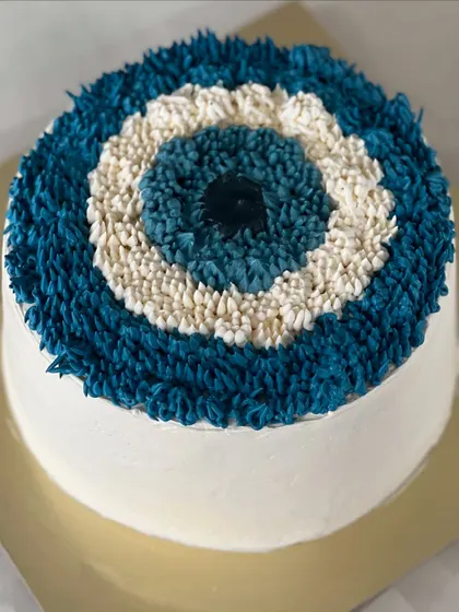 An evil eye theme cake, designed with intricate piping to create the iconic symbol. It's a unique and meaningful design for a special occasion, made to protect and celebrate.