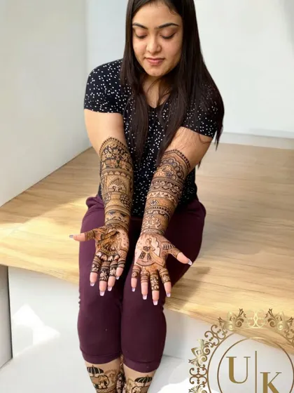 A happy bride showing her full bridal mehandi, complete with detailed designs on her hands and feet. It's always a joy to see the final result on a smiling bride.