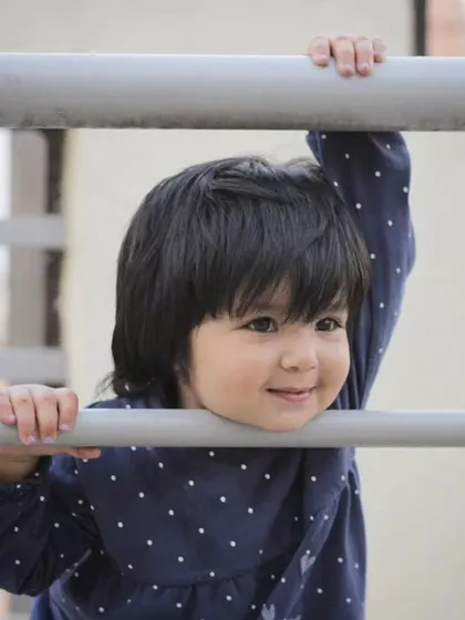 A sweet, candid portrait of a young girl peeking through a railing. These are the quiet, natural moments that often make for the most memorable children's portraits.