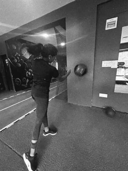 A client performs a rotational medicine ball throw against a wall, a great exercise for building power in the core and upper body.