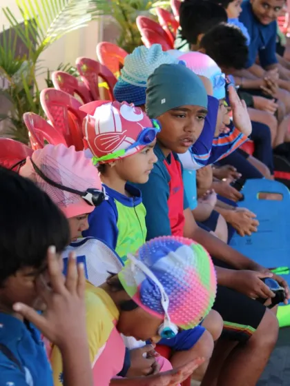 A group of students listens attentively to instructions from the poolside. Dry-land and poolside briefings are an important part of our curriculum, ensuring safety and understanding.